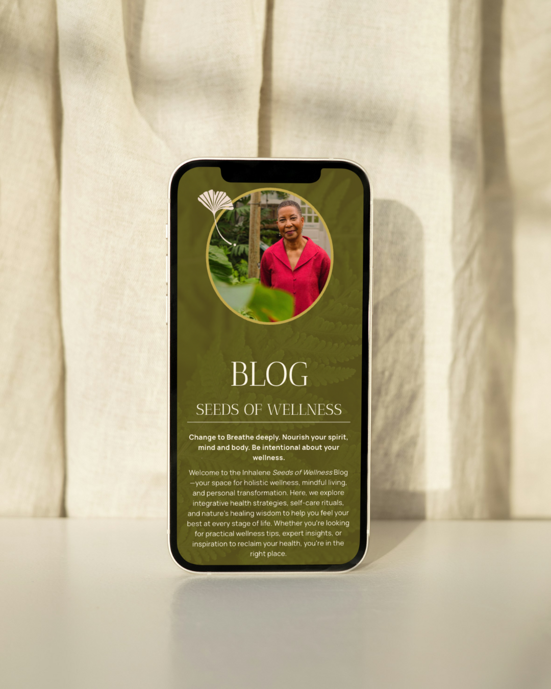 a mobile phone set against a wall of wood displaying the website for Inhalene Health and Wellness Coaching