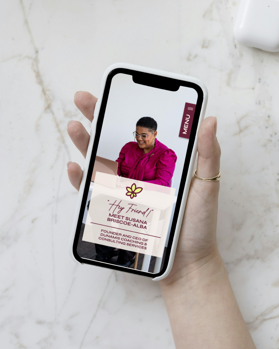 a woman holding a phone on the phone the screen is displaying the website for Dunamis Coaching and Consulting