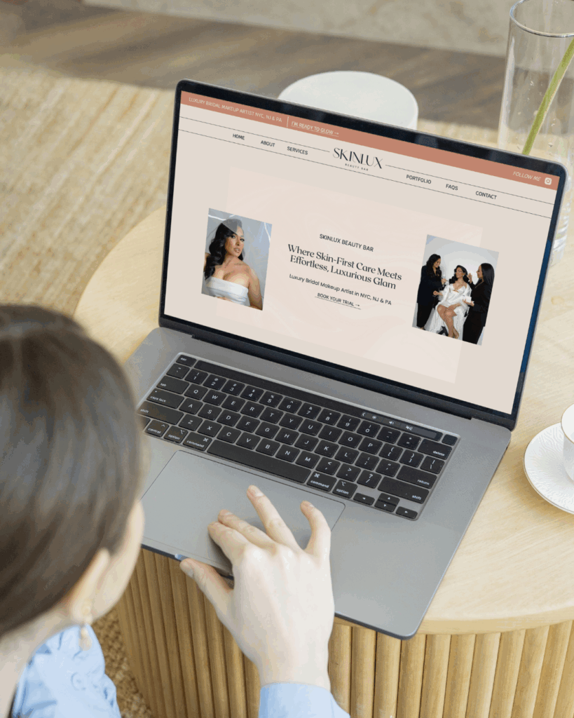 a laptop displaying the website for skinlux beauty hair and make up artist in NYC set on a wood table