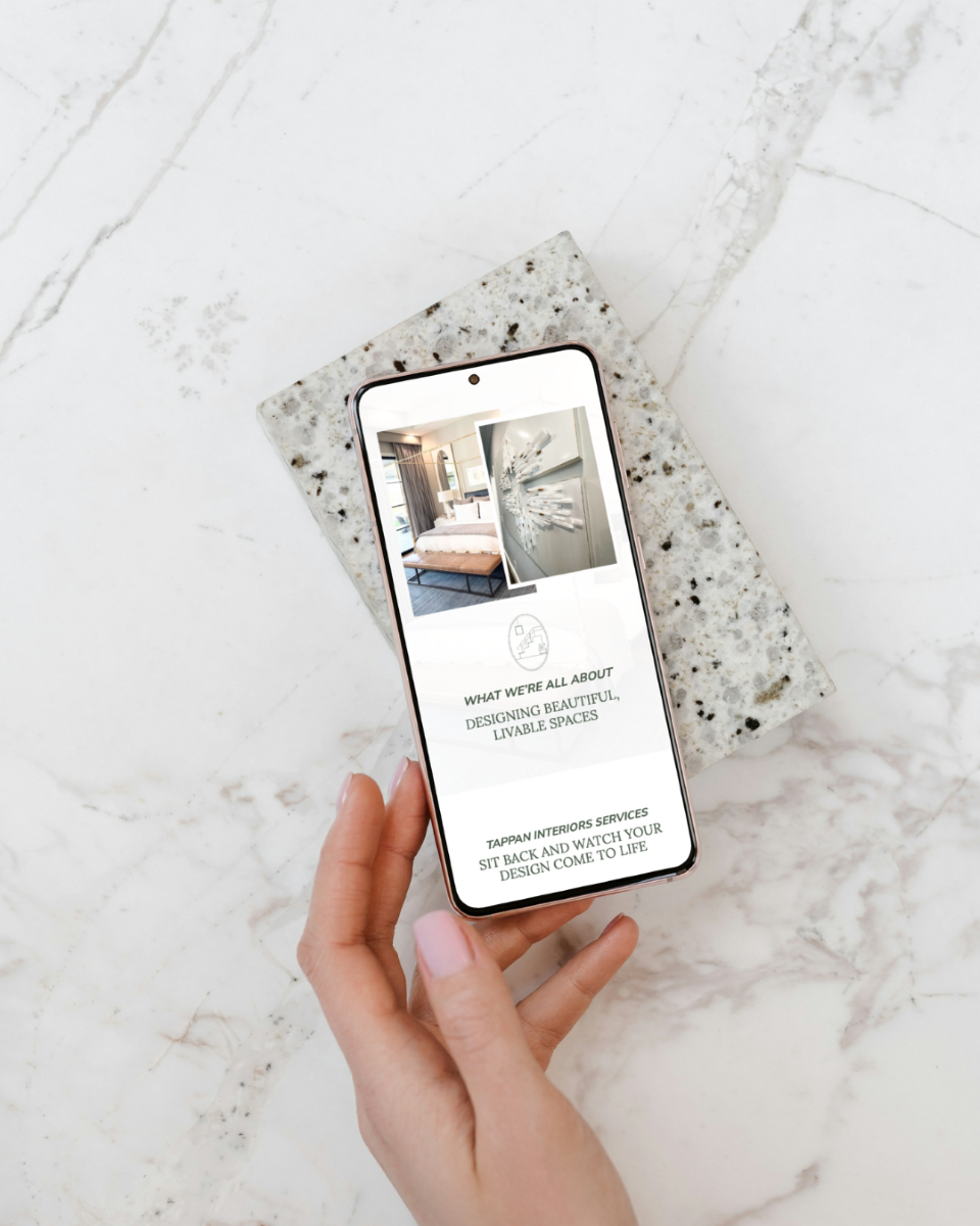 a women holding a phone looking at the website for tappan interiors design and renovation